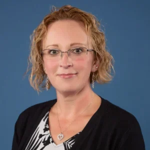 A woman with red hair and glasses is wearing black.